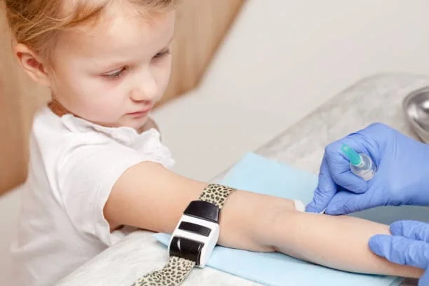 A phlebotomist collecting a blood sample from a young child at home
